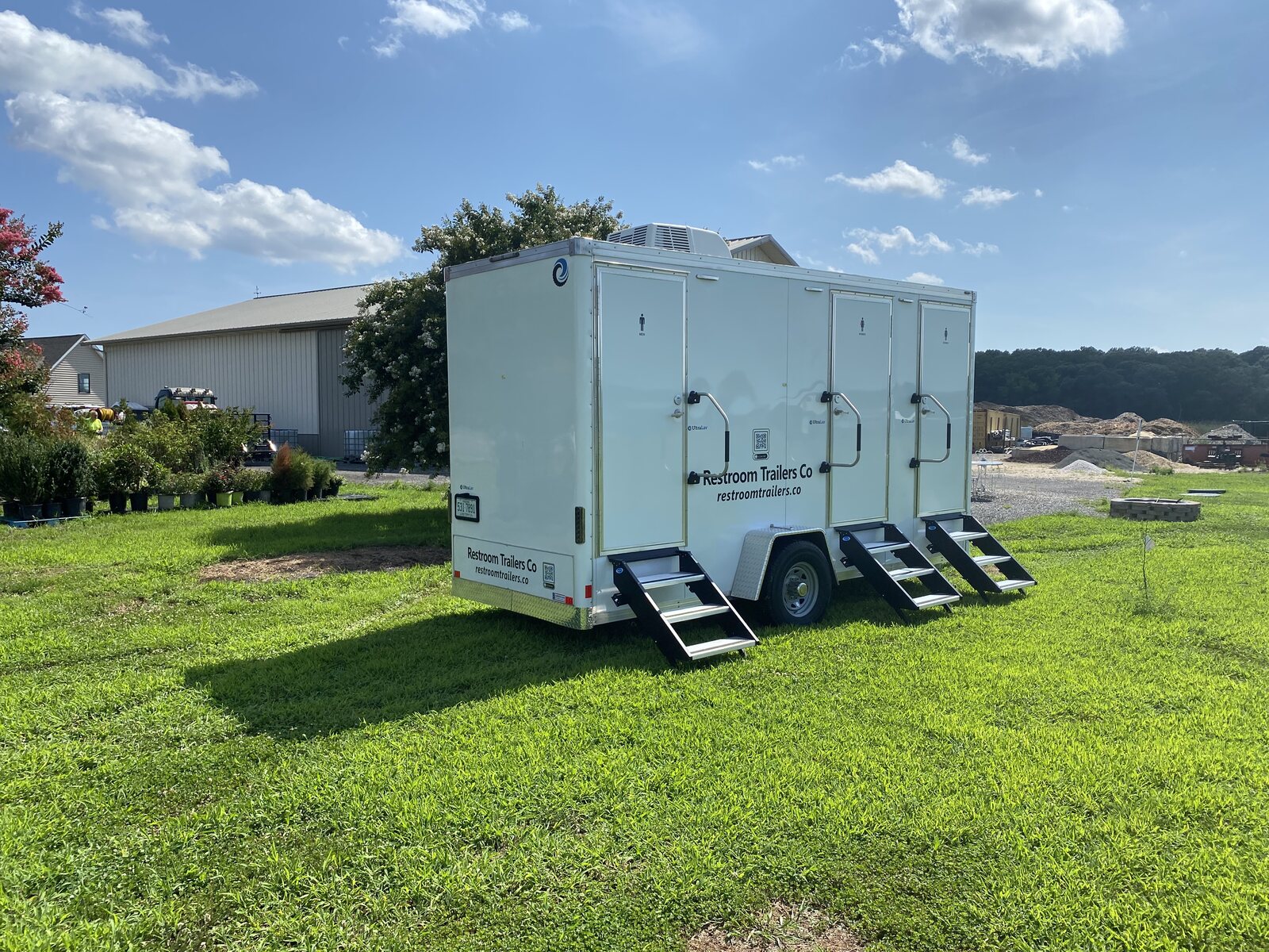 White Restroom Trailers Co. restroom trailer with its steps down, parked on a mowed lawn