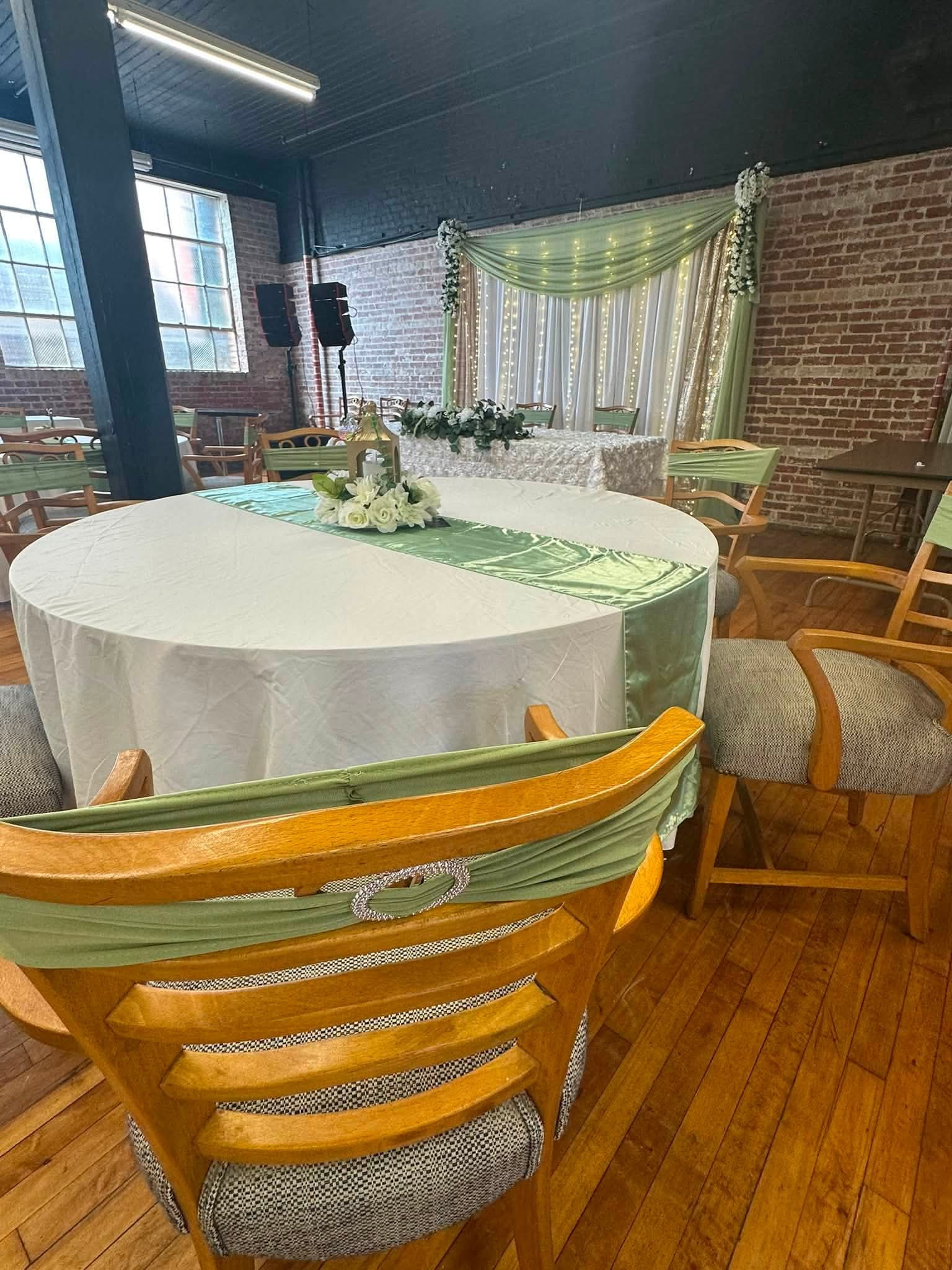 Guest table with sage satin runner, gold lantern and white roses at a Cambridge MD wedding reception